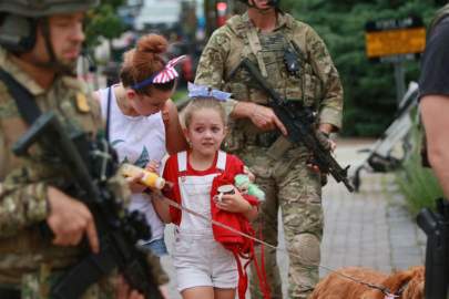 © Mark Borenstein/Getty Images Law enforcement escort a family away from the scene of a deadly shooting at a Fourth of July parade on July 4, 2022 in Highland Park, Ill.